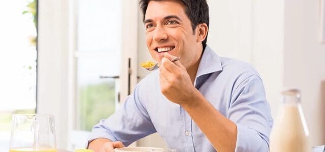 Hombre con implantes dentales comiendo Hombre masticando con implantes dentales